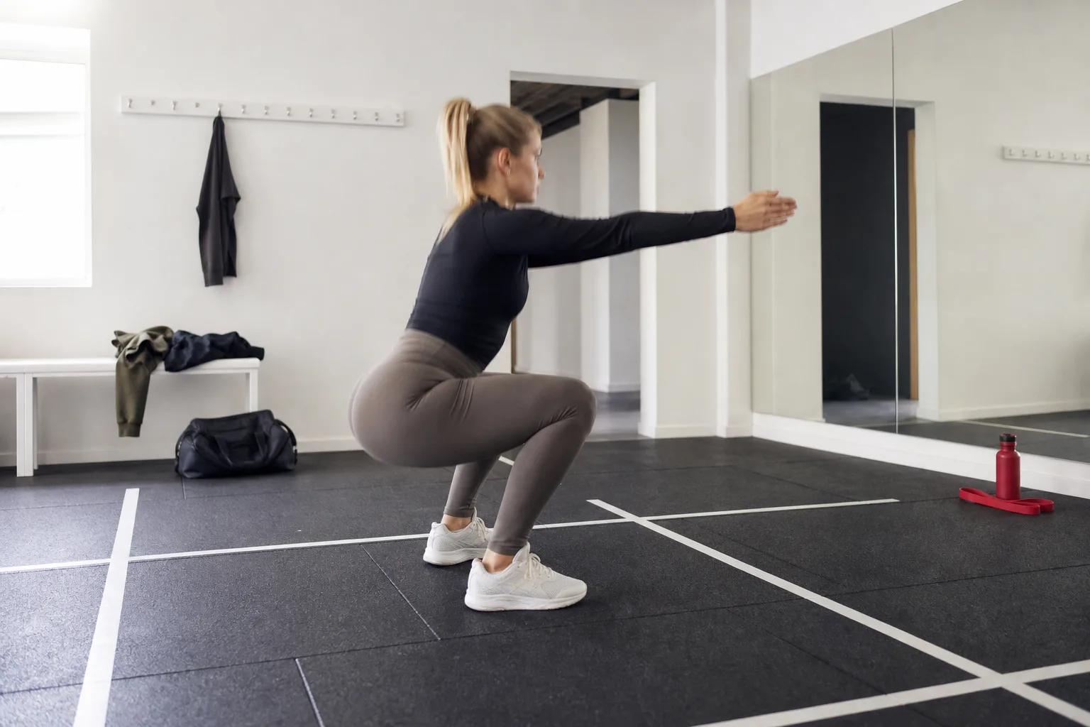 Person i sidovy gör knäböj i högmidjade tights